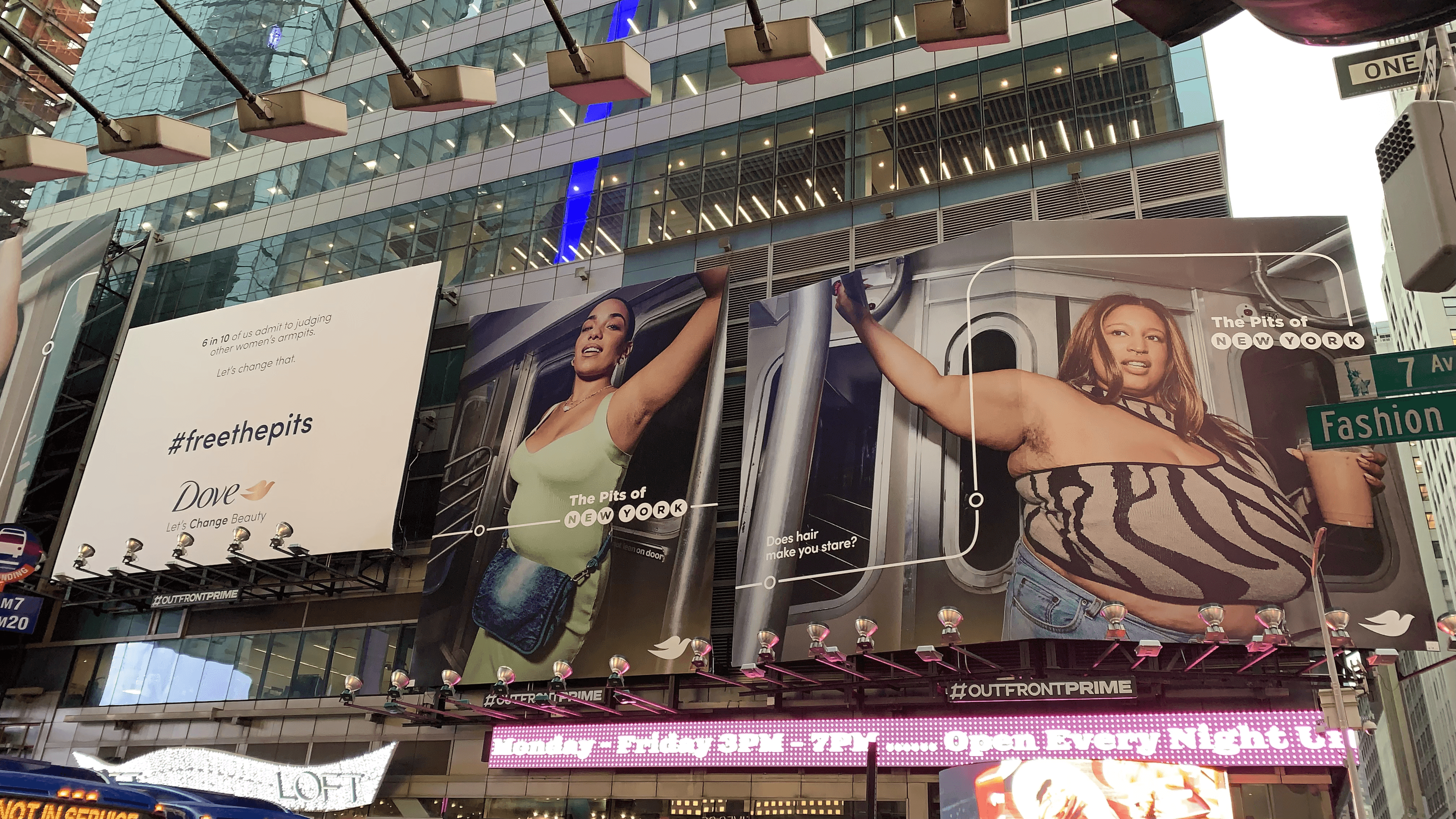 A wide-angle shot of large outdoor billboards in New York City for Dove's "#freethepits" campaign. The left panel features a white background with text about the judgment of women's armpits, while the right panels show two diverse women in a subway car with their arms raised, showing natural armpit hair. The text reads "The Pits of NEW YORK.